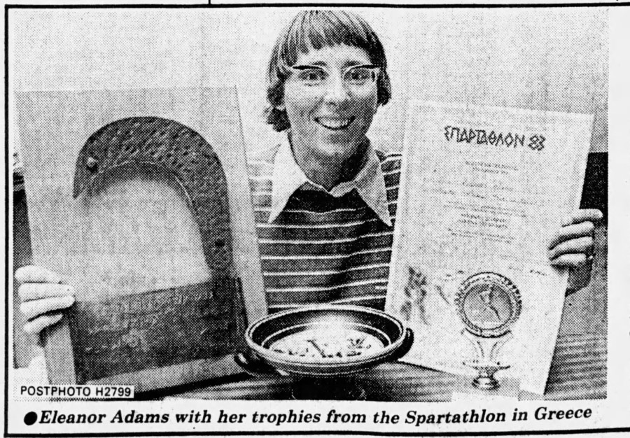 Eleanor Adams holds two certificates from the 1983 Spartathlon and small dish is in front of her.