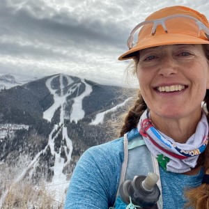 Sarah Lavender Smith trail runner and ultrarunner wearing an orange cap and running gear and smiling