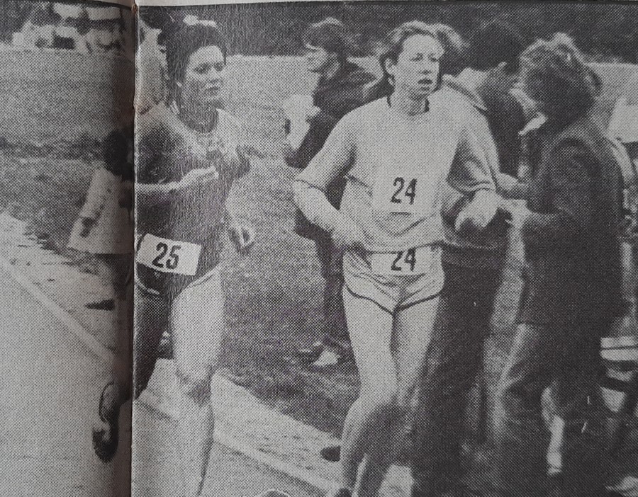 A grainy black and white photograph showing women ultrarunners Ros Paul and Lynn Fitzgerald running side by side in the Gloucester 24 Hour Track race in 1982